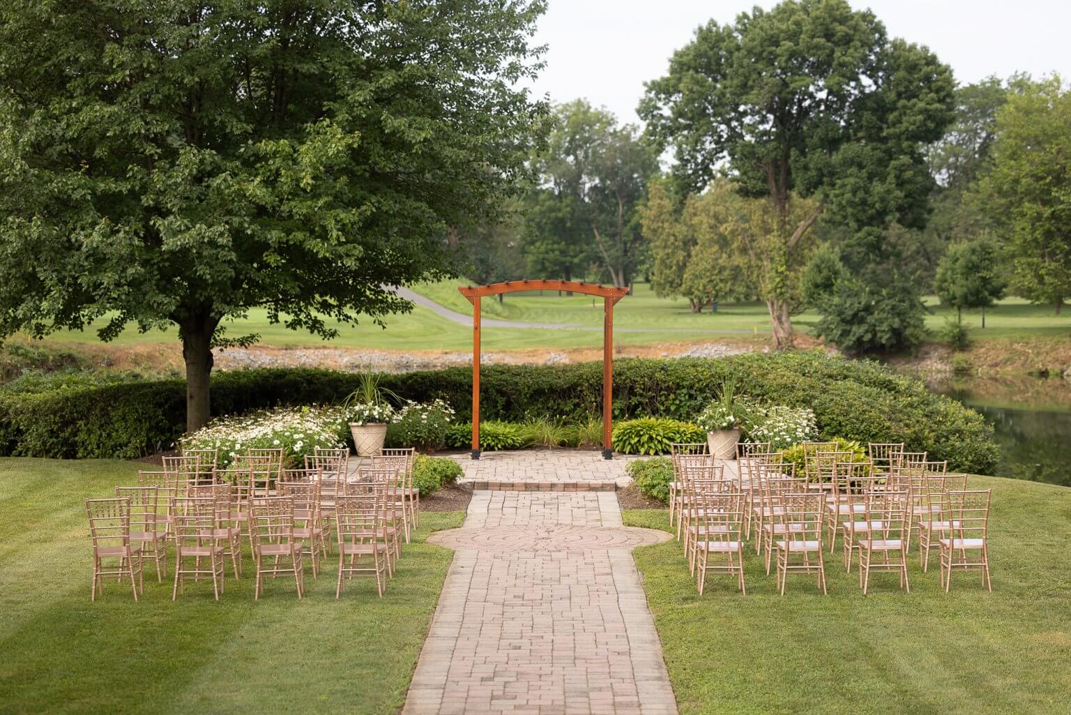 Gold chairs, wooden arbor and a path to the vows