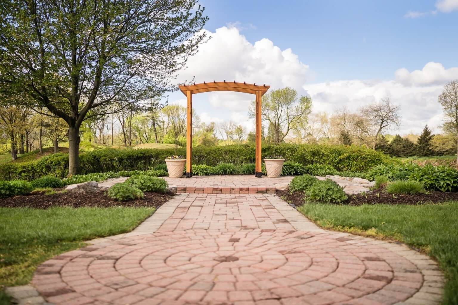 Brick path to the wooden arch on the lawn